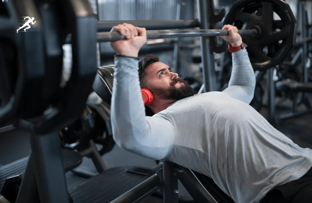 Image of a guy trying to push his PR on bench press while listening to hardcore music