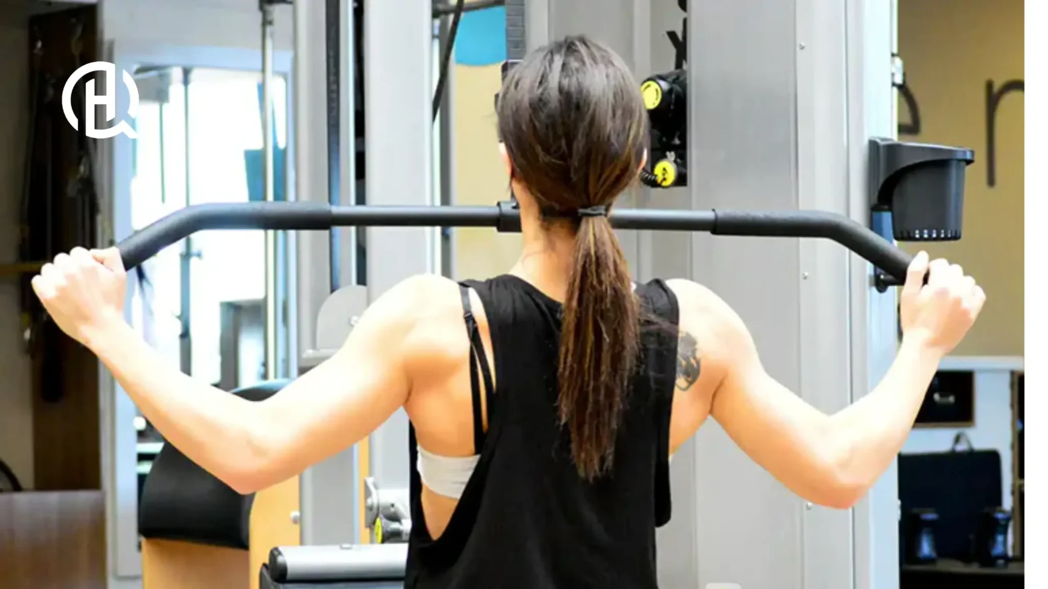 Athlete performing wide-grip pulldown with tattoo visible